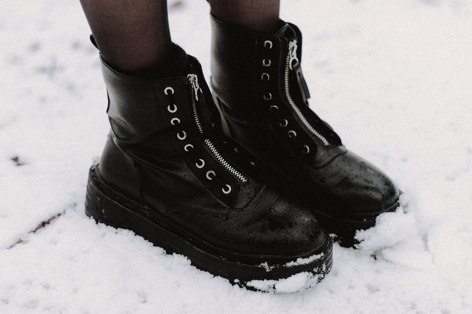 Crop person in leather boots on snowy land